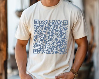 Może przedstawiać: Biała koszulka z nadrukowanym niebieskim kodem QR z przodu.
