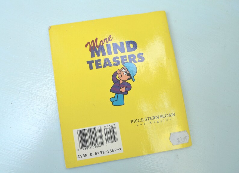 May include: A yellow paperback book titled "More Mind Teasers" with a cartoon illustration of a person wearing a blue hat and a purple and blue striped shirt. The book is published by Price Stern Sloan in Los Angeles. The ISBN is 0-8431-1567-X and the price is $3.95.