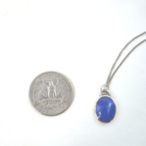 May include: A silver chain necklace with a pendant featuring a blue oval-shaped stone.