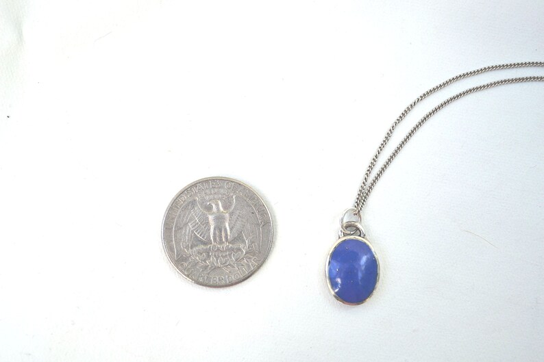 May include: A silver chain necklace with a pendant featuring a blue oval-shaped stone.