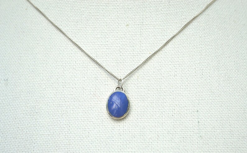 May include: A silver chain necklace with a blue oval pendant.