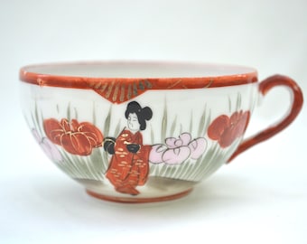 Könnte beinhalten: Eine weiße Porzellantasse mit rotem und goldenem Rand. Die Tasse ist mit einer handgemalten Szene einer Frau in einem roten Kimono verziert, die in einem Feld mit rosa und roten Blumen steht.