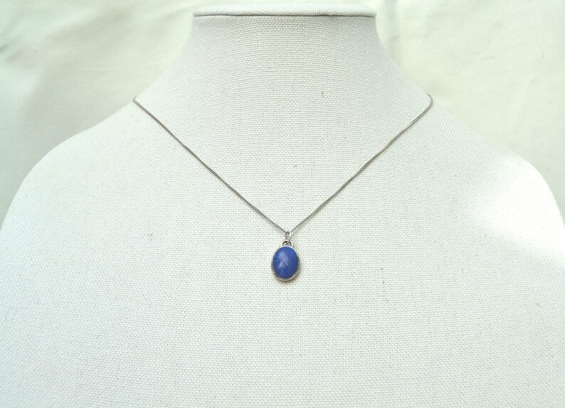 May include: A silver chain necklace with a blue oval pendant.