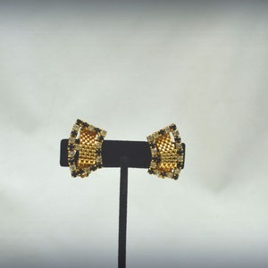 May include: A pair of gold tone clip-on earrings with black and clear rhinestones.