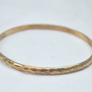 Op de afbeelding: Een gouden armband met een getextureerde, gehamerde afwerking.