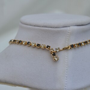 May include: A gold necklace with a chain of alternating black and clear rhinestones. The necklace has a simple clasp.