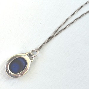 May include: A silver chain necklace with a pendant featuring a blue oval stone.