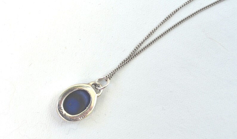 May include: A silver chain necklace with a pendant featuring a blue oval stone.