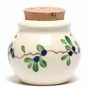 May include: A white ceramic jar with a cork lid and a blue and green floral design. The jar has holes in the side for ventilation.
