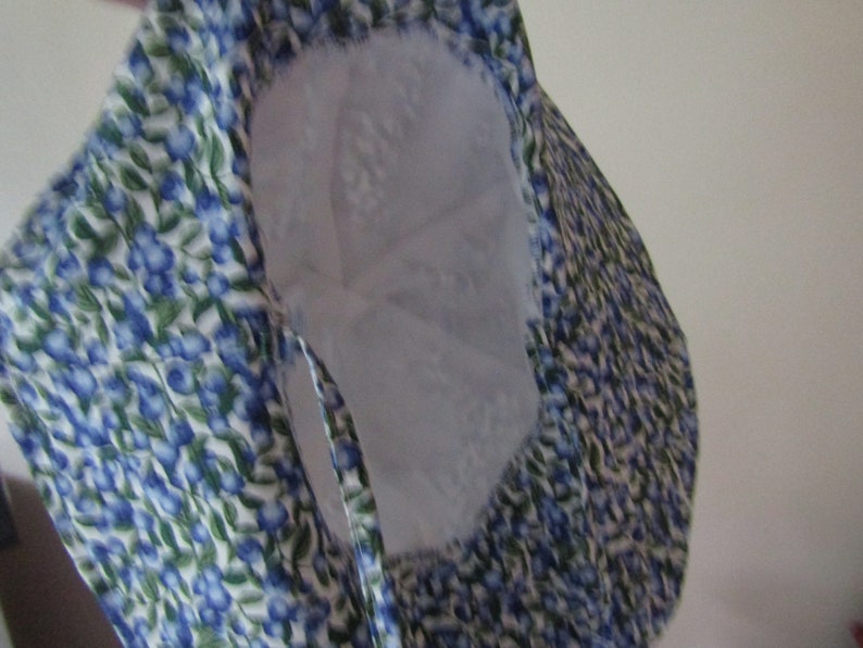 Peut inclure: Un chapeau seau en tissu blanc avec un imprim&eacute; floral bleu et vert. Le chapeau a une large bordure et un cordon de serrage.