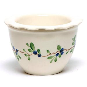 Puede incluir: Un tazón de cerámica blanco con un borde festoneado y un diseño floral azul y verde. El tazón está decorado con un patrón repetitivo de bayas azules y hojas verdes.
