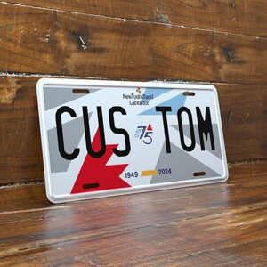May include: A rectangular license plate with the word "CUSTOM" in large black letters. The plate features a red and white design, the text "Newfoundland Labrador", and the numbers "1949" and "2024".