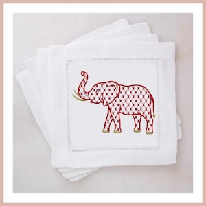 Könnte beinhalten: Ein Stapel weißer quadratischer Cocktailservietten aus Leinen. Jede Serviette zeigt einen gestickten roten Elefanten mit einem Gittermuster. Der Elefant hat goldene Stoßzähne und blaue Augen. Die Servietten haben eine dekorative Naht.