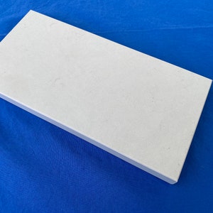 May include: A white rectangular tile with a slightly textured surface.