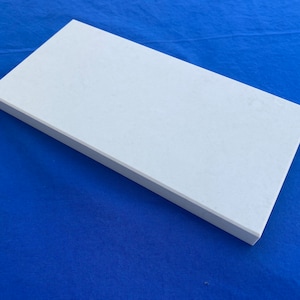 May include: A white rectangular ceramic tile with a smooth, slightly textured surface.