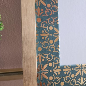 May include: Gold picture frame with a teal and gold patterned border. The frame has a brushed gold finish.