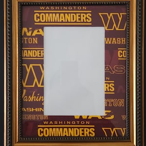 Könnte beinhalten: Ein gerahmtes Bild mit dem Logo und Namen der Washington Commanders in Gold und Weiß auf burgunderrotem Hintergrund. Der goldene Rahmen hat eine dekorative Bordüre und die Mitte einen weißen Bereich für ein Foto.