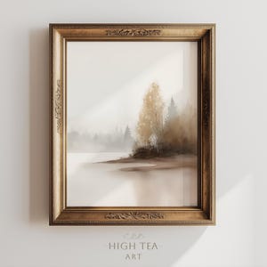 Op de afbeelding: Een ingelijste landschapskunstafdruk met een serene, mistige meerzicht met bomen in bruin- en grijstinten. Het kunstwerk is ingesloten in een goudkleurige, sierlijke lijst. De tekst "HIGH TEA ART" staat onderaan.