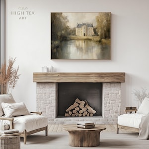 May include: A painting of a large, light-colored building with a reflection in the water in front of it. The building has a pointed roof and many windows. The painting is hanging above a fireplace with a wooden mantel and a stone surround. There are two white armchairs in front of the fireplace.