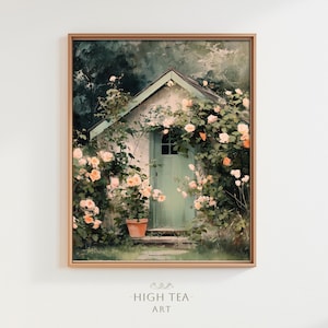 Pode incluir: Uma impressão de arte emoldurada de uma pequena casa de campo com uma porta verde, rodeada por rosas trepadeiras em tons de pêssego e branco. A obra de arte tem um estilo suave e pictórico, com o texto "HIGH TEA - ART" na parte inferior.