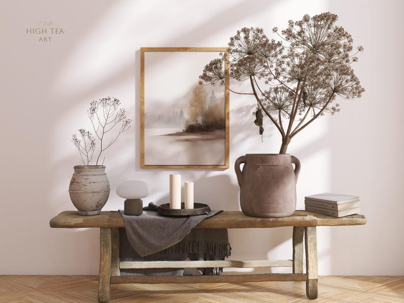 Op de afbeelding: Een rustieke houten bank toont een ingelijste landschapskunst, droge bloemstukken in keramische vazen, kaarsen en boeken. Een kleine lamp en een donkergrijze deken maken de decoratie compleet. De tekst "HIGH TEA ART" is zichtbaar.