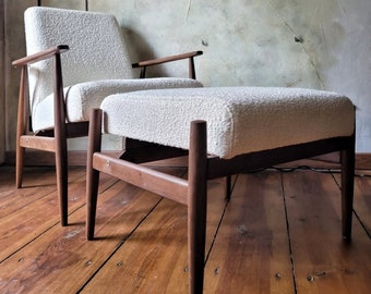May include: A white upholstered armchair and footstool with dark wood legs. The chair and footstool have a textured fabric.
