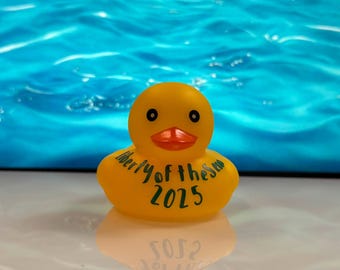 Puede incluir: Un patito de goma amarillo con ojos negros y pico naranja. El pato tiene las palabras "Liberty of the Sea 2025" impresas en el pecho. El fondo es una escena de agua azul.