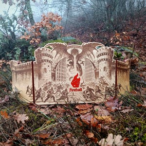 May include: A cardboard display featuring a castle design with a dragon and warriors, with the word "Fireball" and a red flame logo. The display is set in a natural outdoor environment with foliage.