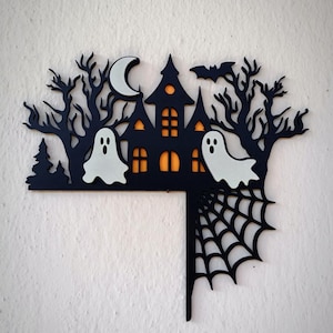 Peut inclure: Décoration noire d'Halloween représentant une maison hantée, des arbres, une chauve-souris, une lune, deux fantômes et une toile d'araignée. La maison a des fenêtres orange. Les fantômes et la lune sont blancs. Parfait pour Halloween.