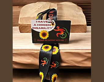 May include: Black lanyard with sunflowers and a red, green, and yellow symbol. A white card attached to the lanyard reads "I have a hidden disability. Please be patient with me".