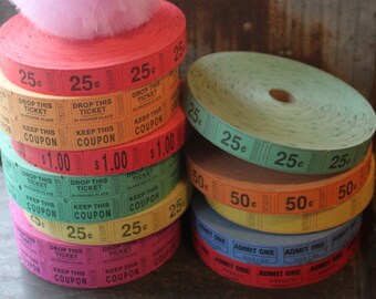 May include: A stack of colorful ticket rolls with different denominations, including 25 cents, 50 cents, and $1.00. The rolls are stacked on top of a pink tulle pom-pom.