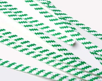 May include: White and green zigzag patterned shoelaces. The shoelaces are made of a flat, woven material and are arranged diagonally across the frame. The green pattern is a series of chevrons.