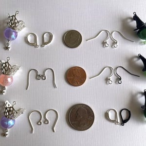 May include: An assortment of jewelry components, including three pairs of earrings with silver crowns and colorful beads, earring hooks, and coins. Also included are witch-themed earrings with green glass beads and black hats.
