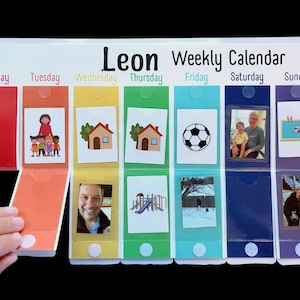 May include: A personalized weekly calendar for Leon, featuring colorful days of the week. Each day has a pocket with a picture or illustration, including a soccer ball, house, and family photos. The calendar is designed to help organize daily activities.