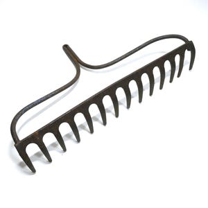 May include: An old, rusty metal garden rake. It has a curved handle and a row of curved tines. The rake is made of dark metal and is set against a white background. The tines are evenly spaced.