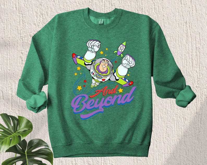 May include: Green sweatshirt with a cartoon image of Buzz Lightyear from Toy Story flying with the text "And Beyond".