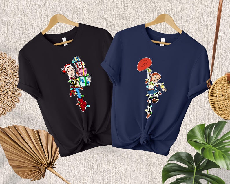 May include: Two t-shirts with Christmas-themed Toy Story characters. The black shirt features Woody holding presents and the navy blue shirt features Jessie holding a red star.