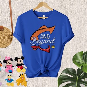 May include: A royal blue t-shirt with a cartoon image of a cowboy hat and the text "AND BEYOND".
