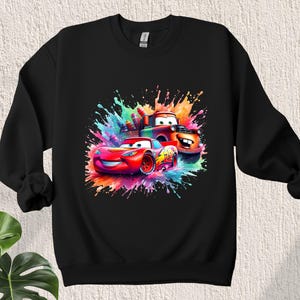 May include: Black sweatshirt with a colorful graphic of Lightning McQueen and Mater from the Cars movie. The graphic features a splash of paint effect.