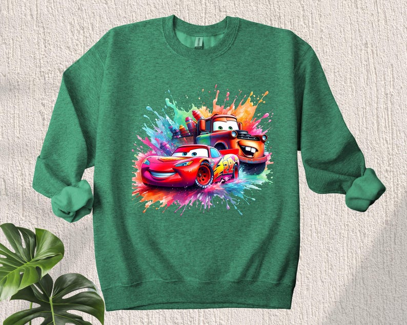 May include: Green sweatshirt with a colorful graphic of two cartoon cars, one red and one orange, with paint splatters in the background.
