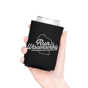 Puede incluir: Un enfriador de latas negro con el texto blanco "Run Wisconsinbly" y un contorno blanco del estado de Wisconsin. El enfriador de latas está en la mano de una persona.