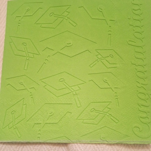 May include: Green foam sheet with a repeating pattern of graduation caps and the word "Congratulations" embossed on the right side.