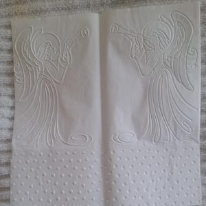 Pu&ograve; includere: Due fogli di carta bianca con disegni di angeli in rilievo. Ogni angelo suona la tromba, con ali e vesti dettagliate. La parte inferiore di ogni foglio presenta un bordo a pois, creando un effetto strutturato.