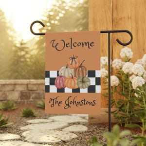 Może przedstawiać: Flaga ogrodowa z napisem "Welcome The Johnstons" na tle w kratkę i stosem dyni.