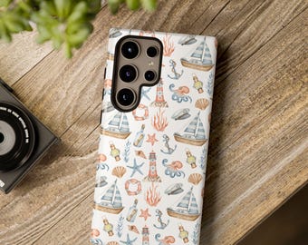 Puede incluir: Una funda de teléfono blanca con un diseño náutico que presenta veleros, anclas, faros y conchas marinas. La funda tiene un recorte para la cámara y está colocada sobre una superficie de madera. El diseño incluye elementos azules, marrones y rojos.