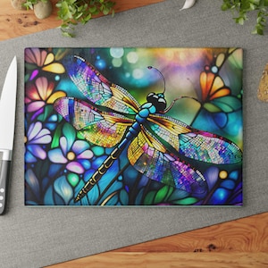 May include: A colorful stained glass dragonfly with blue, yellow, green, and purple accents. The dragonfly is set against a background of flowers and leaves.