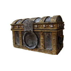 May include: A decorative wooden chest with a hinged lid and metal accents. The chest features a weathered, aged appearance with silver-colored metal bands and rivets. The front has a large, circular lock and ornate carvings.