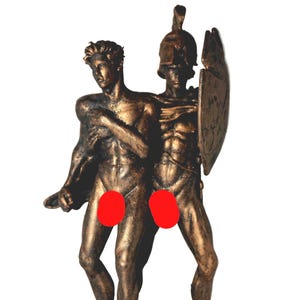 May include: A bronze-toned sculpture depicting two figures standing side by side. One figure is bareheaded, while the other wears a helmet and carries a shield. Both figures have muscular builds and are partially obscured by red circular overlays.