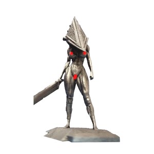 May include: A silver figurine of a humanoid figure with a pyramid-shaped head and a large sword. The figure is standing on a small, grey base. The figure has red markings on the chest and groin.