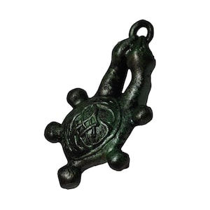 May include: A bronze turtle pendant with a loop. The turtle's shell has a detailed Celtic knot design. The pendant has a weathered look, possibly vintage. The design is intricate and artistic. The pendant is likely made of bronze or a similar metal.